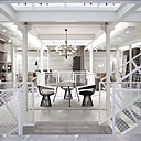 L’escalier métallique immaculé doté de hauts garde-corps qui laisse passer la lumière relie tous les espaces. Au centre, fauteuils en fils d’acier de Warren Platner édités par Knoll et lustre 2097 de Gino Sarfatti édité par Flos.