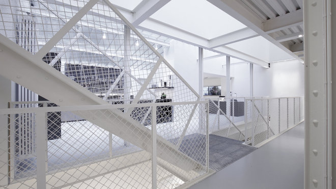 La charpente métallique et les garde-corps ajourés peints en blanc allègent l’espace et composent une toile de fond neutre pour mettre en valeur tous les matériaux diversifiés des créations présentées.