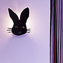 Détail d’une applique lumineuse, dessiné comme un masque de fête.