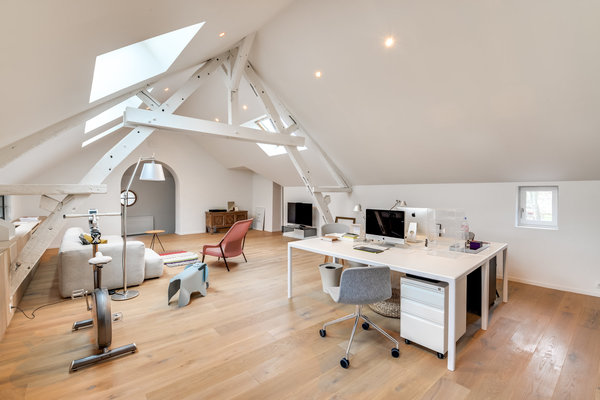 Chaque espace a été repensé. Les clients désiraient des pièces claires et simples.  L’architecte Thibault de Montmarin a utilisé très peu de couleurs et de matériaux. Les murs et les poutres sont simplement peints en blanc pour créer une atmosphère très épurée. Et c'est le mobilier qui anime l'espace. Sous la poutraison repeinte, un grand espace qui profite de belle géométrie de la charpente.