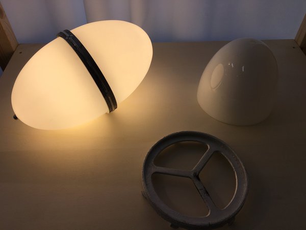 Lampe MW33, en verre et aluminium. Ce modèle qui utilise la technologie LED est composé de 2 verres elliptiques reliés par une bague. Elle peut simplement se poser au sol ou s’accrocher au plafond. Création Peter Ghyczy, 2015.