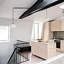 L’îlot mobile sur roulettes permet une certaine modularité de l’espace. La lampe sur mesure, dessinée par Joseph Grappin, est conçue sur le principe de l’équilibre en porte-à-faux de deux globes en opaline qui chevauchent la charpente entre la montée d’escalier et l’îlot de la cuisine. Ils sont suspendus par un fil textile noir avec un tube d’acier qui sert de contrepoids. Suspension lumineuse PH Artichoke, création Poul Henningsen éditée par Louis Poulsen.