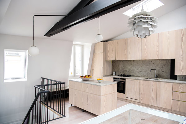 L’îlot mobile sur roulettes permet une certaine modularité de l’espace. La lampe sur mesure, dessinée par Joseph Grappin, est conçue sur le principe de l’équilibre en porte-à-faux de deux globes en opaline qui chevauchent la charpente entre la montée d’escalier et l’îlot de la cuisine. Ils sont suspendus par un fil textile noir avec un tube d’acier qui sert de contrepoids. Suspension lumineuse PH Artichoke, création Poul Henningsen éditée par Louis Poulsen.