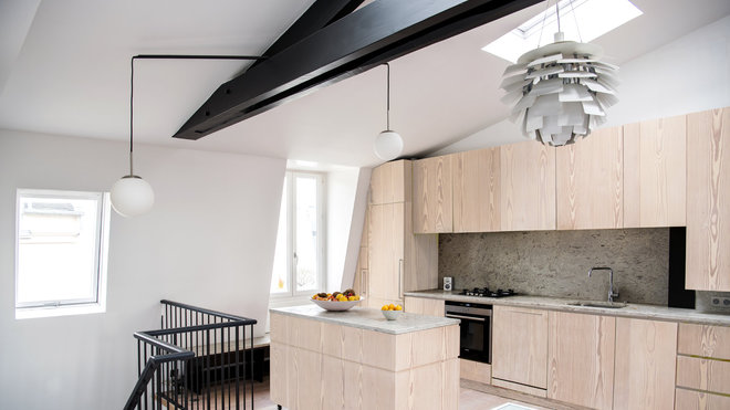 L’îlot mobile sur roulettes permet une certaine modularité de l’espace. La lampe sur mesure, dessinée par Joseph Grappin, est conçue sur le principe de l’équilibre en porte-à-faux de deux globes en opaline qui chevauchent la charpente entre la montée d’escalier et l’îlot de la cuisine. Ils sont suspendus par un fil textile noir avec un tube d’acier qui sert de contrepoids. Suspension lumineuse PH Artichoke, création Poul Henningsen éditée par Louis Poulsen.