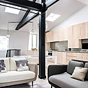 Le salon s’articule autour de deux canapés qui créent un coin cosy accentué par la présence d’une cheminée à l’éthanol. Dans le linéaire des rangements de la cuisine, un plateau coulissant avec rangement offre un coin bureau gain de place et escamotable.