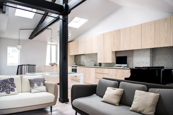 Le salon s’articule autour de deux canapés qui créent un coin cosy accentué par la présence d’une cheminée à l’éthanol. Dans le linéaire des rangements de la cuisine, un plateau coulissant avec rangement offre un coin bureau gain de place et escamotable.