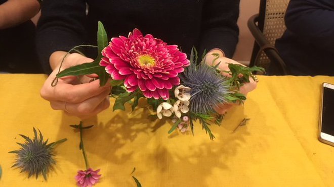 Un mélange de fleurs et végétaux s'imbriquent sur le devant de la couronne.