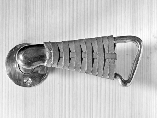 Gros plan sur une poignée de porte recouverte d’un tressage de cuir de la maison Louis Carré, à Bazoches-sur-Guyonne en région parisienne. Création Alvar Aalto, 1956-1959, 1961-1963.