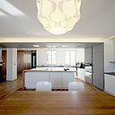 La cuisine est connectée avec la salle à manger. Les chaises de couleur blanche font écho à celle des rangements.