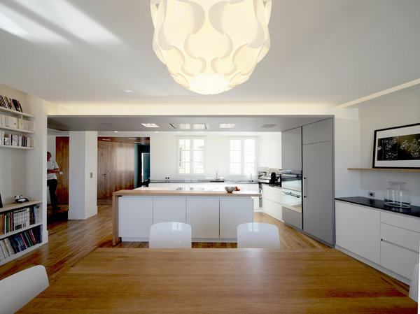 La cuisine est connectée avec la salle à manger. Les chaises de couleur blanche font écho à celle des rangements.