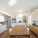 La décoration de la pièce à vivre mêle bois clairs et tonalités de blanc soulignés par quelques touches de noir pour dessiner un espace graphique et clair aux fonctions parfaitement lisibles.