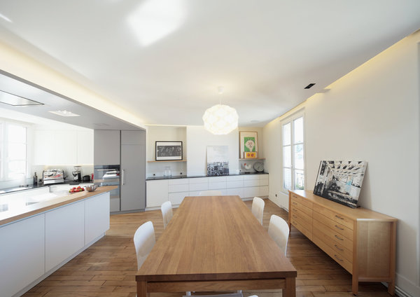 La décoration de la pièce à vivre mêle bois clairs et tonalités de blanc soulignés par quelques touches de noir pour dessiner un espace graphique et clair aux fonctions parfaitement lisibles.