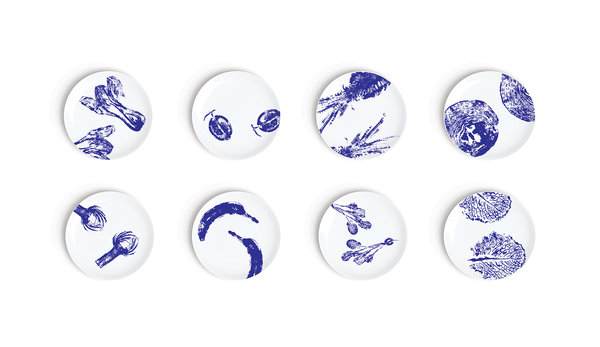 Collection Végétal aux motifs conçus avec des fruits et des légumes tranchés puis trempés dans l’encre bleue comme des tampons pour former des empreintes estompées et des effets de végétaux fossilisés. Set de 8 assiettes à dessert. Création Chiara Andreatti pour Non Sans Raison.