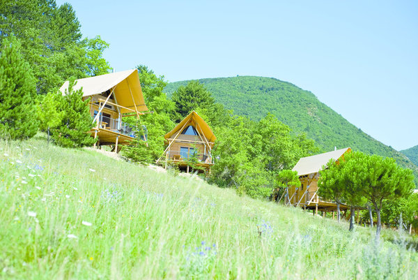 Surmontées d’une toile de tente qui cache les chambres, Cahuttes Huttopia à Dieleufit, en Drôme provençale.