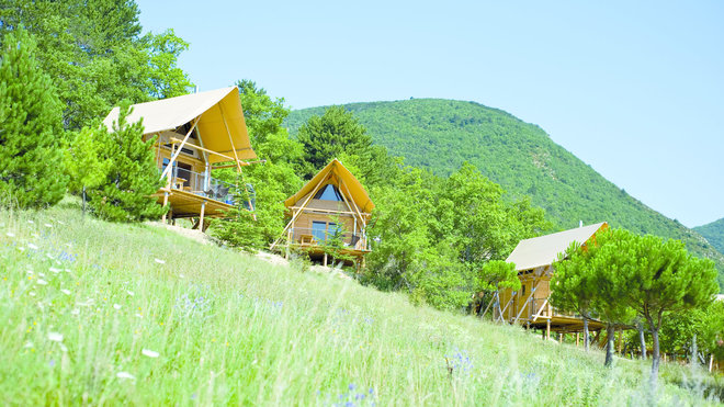 Surmontées d’une toile de tente qui cache les chambres, Cahuttes Huttopia à Dieleufit, en Drôme provençale.