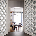 Vue de la salle à manger à travers l’ouverture de la salle de bains qui, comme une fenêtre, offre de volets intérieurs battants.