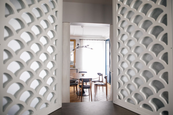 Vue de la salle à manger à travers l’ouverture de la salle de bains qui, comme une fenêtre, offre de volets intérieurs battants.