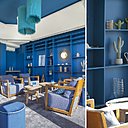 Dans le salon baptisé Les Heures Bleues, bibliothèque sur mesure, fauteuils existants recouverts de tissu Casamance avec petites tables basses et poufs de chez Lazare Home.