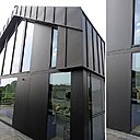 La maison est revêtue de panneaux en acier peint en noir ponctué de bois qui brise son côté métallique.