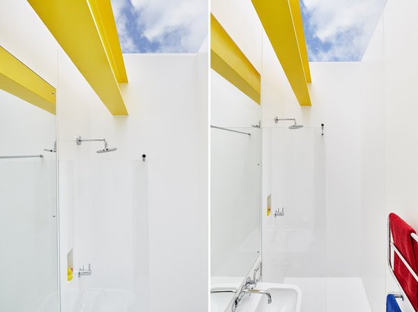 Dans les deux salles de bains, ouvertes sur le jardin, les poutres en acier apparentes, peintes en jaune, font partie de l’ADN de la maison d’origine.