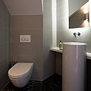 Dans le cabinet de toilette, vasque (référence WT.R400K 450300000), Agape et tablette en Corian® avec éclairage rétroactif placé derrière le miroir. Mitigeur Vola avec bec fixe. Toilettes suspendues (cuvette # 222709, Starck 3 chez Duravit avec plaque de déclenchement Sigma 20 chez Geberit) qui facilitent le nettoyage et placards muraux très pratiques.
