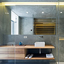 Derrière sa cloison vitrée, l’espace salle de bains est nappé d’un enduit de béton.