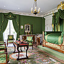 Dans la chambre parentale, mobilier de style Empire avec lit sur estrade, consoles, psyché, soieries tapissant les murs et ciel de lit aux retombées lourdement chargées de passementerie.