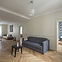 Le salon traversant, de façade à façade, bénéficie de deux orientations et de deux fenêtres qui compensent sa relation étroitesse. En position centrale au cœur de l’espace, il a été aménagé et meublé dans sa longueur. D’un côté, il s’ouvre sur la cuisine-salle à manger, de l’autre sur les chambres. Les ouvertures initiales ont été conservées, mais les portes supprimées pour élargir les espaces tout en longueur et rééquilibrer leurs proportions. Au plafond, suspensions, modèle Naranza, ches Vistosi.