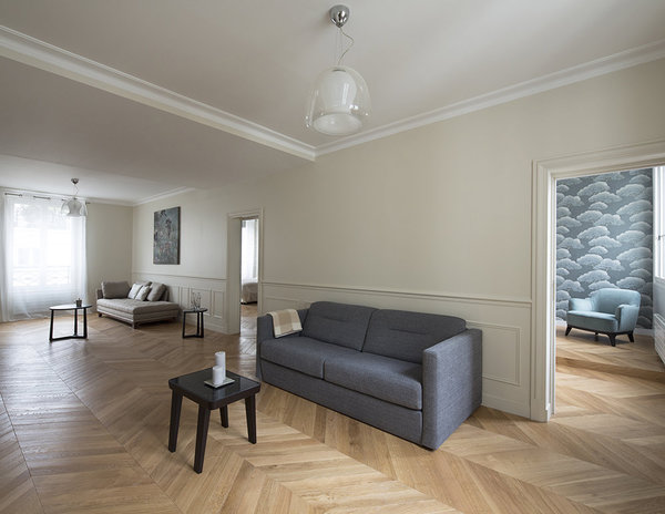 Le salon traversant, de façade à façade, bénéficie de deux orientations et de deux fenêtres qui compensent sa relation étroitesse. En position centrale au cœur de l’espace, il a été aménagé et meublé dans sa longueur. D’un côté, il s’ouvre sur la cuisine-salle à manger, de l’autre sur les chambres. Les ouvertures initiales ont été conservées, mais les portes supprimées pour élargir les espaces tout en longueur et rééquilibrer leurs proportions. Au plafond, suspensions, modèle Naranza, ches Vistosi.