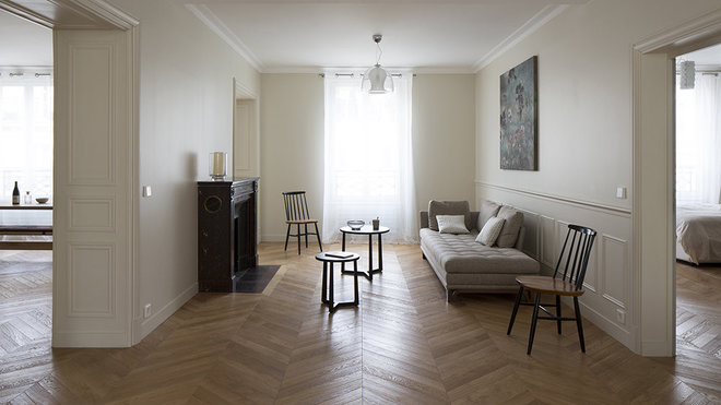 La seconde partie du salon profite d’une nouvelle cheminée ancienne en marbre rouge de style Louis XVI, chinée. Ses lignes sont plus droites que celles du modèle existant, une banale cheminée en marbre blanc jauni de style Louis XV. Devant, le tapis a été aussi refait pour s’harmoniser avec la nouvelle implantation. La décoration épurée met en valeur les traces du passé. Le raffinement des murs peints en crème et le plafond blanc immaculé créent un léger et subtil effet de contraste.