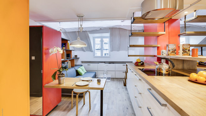 Dans la pièce de vie, l’espace au sol a été uniformisé avec un parquet en chêne et les fenêtres ont été changées. Un totem de rangement structure l’entrée. Des rangements bas (Ikea) exploitent aussi les pans de murs sous la pente du toit.