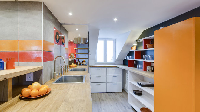 A l’opposé du salon, la cuisine offre un double plan de travail avec des étagères en partie haute.