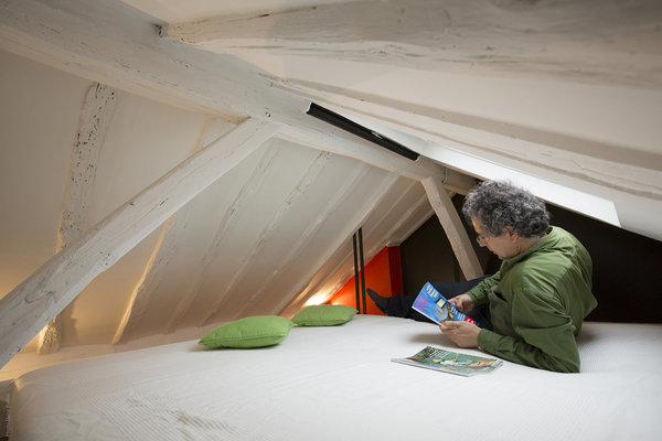 La charpente repeinte en blanc agrandit l’espace. La mezzanine a été agrandie et renforcée par des tirants qui s’encastrent dans la charpente.