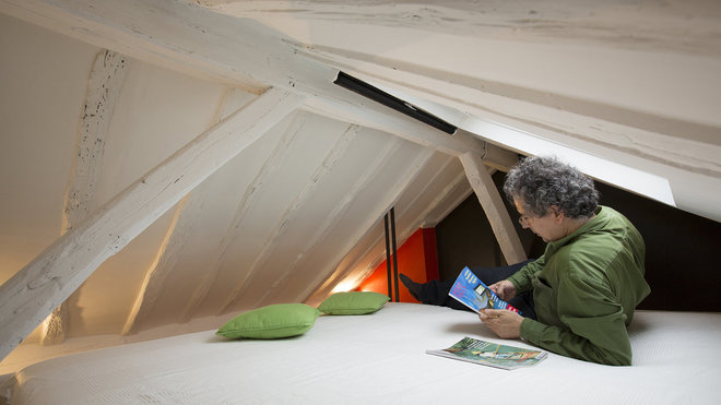 La charpente repeinte en blanc agrandit l’espace. La mezzanine a été agrandie et renforcée par des tirants qui s’encastrent dans la charpente.