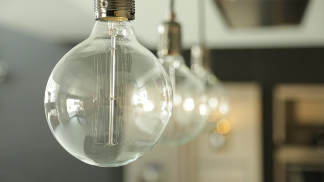 Au-dessus du plan de travail de la cuisine, des suspensions lumineuses mettent en relief un style industriel et la pureté magnifiée des ampoules à incandescence.
