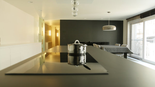 Le coin repas, placé à côté de la zone de préparation de la cuisine et en continuité de son plan de travail en Corian noir, profite de la terrasse  comme le salon.