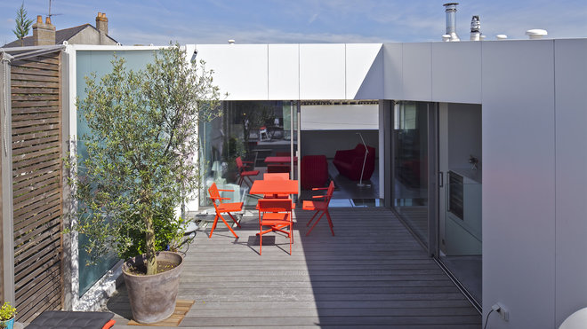 Côté jardin, l’enveloppe marie subtilement deux parements, un bardage en bois et un béton recouvert d’une peinture blanche. Le volume en bois délimite une terrasse en creux, partiellement protégée des vues extérieures et du vent.