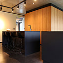 La cuisine est composée de deux blocs monolithiques noir qui contrastent avec le béton et le bois. Réalisation Hornoy Architectes.