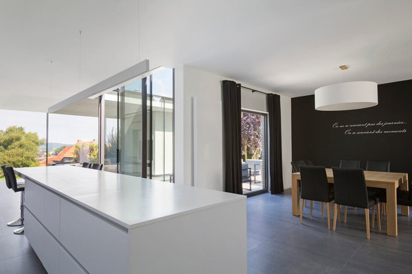 L’îlot de la cuisine est terminé par un bar et une vraie table de repas occupe l’espace de l’ancienne salle à manger. Le sol est composé de grandes dalles de grès cérame.