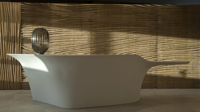 Comptoir de réception de forme organique dessiné par l’agence D.L.2.A devant un mur en bois sculpté.