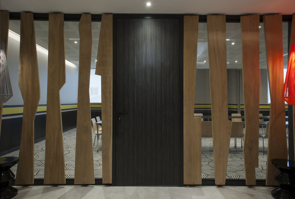 La salle de conférence est partiellement occultée par une cloison en bois ajourée.