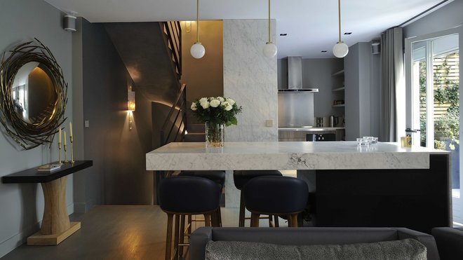 La cuisine s’inscrit naturellement dans l’espace. Sa partie technique est partiellement occultée par un panneau mural en marbre. Suspensions lumineuses, CTO Lighting. Console, Christian Liaigre et miroir, Hervé Van der Straeten.