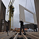 Photo de chantier : démarrage du montage des panneaux par la façade arrière de la surélévation marquée par ses quatre fenêtres asymétriques.
