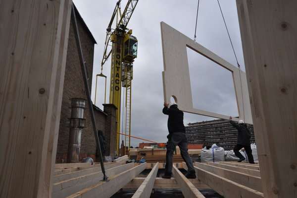 Photo de chantier : démarrage du montage des panneaux par la façade arrière de la surélévation marquée par ses quatre fenêtres asymétriques.