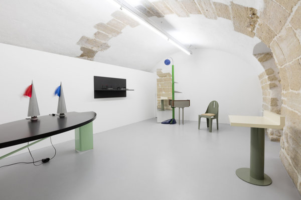 De gauche à droite, table en métal Prima Duna d’Alessandro Mendini, lampes Maestrale de Denis Santachiara, au fond, coiffeuse Grande Specchio (zamac sablé et peint, tôle pliée, métal tubulaire, miroir et noyer) de Paolo Deganello, chaise Biribi et bureau Rif d’Alessandro Mendini, édités en 1985 et 1988 par Tribu.