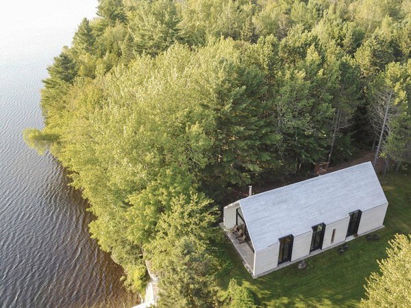 Entouré d’arbres, le chalet au bord du lac est une construction qui entend préserver la nature environnante.