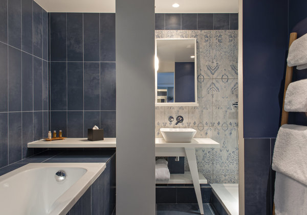 Dans la salle de bains, une fresque en carrelage aux couleurs aquatiques et aux motifs floraux adoucie les lignes très contemporaines de l’espace.