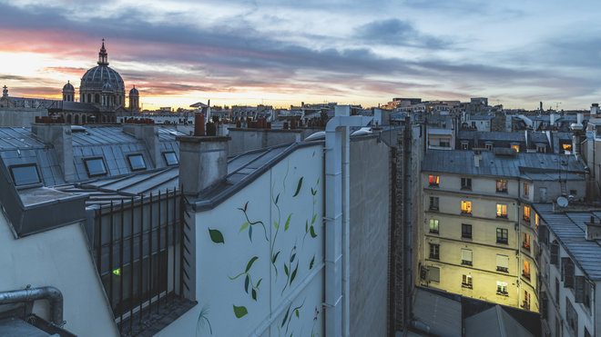 Côté rue, deux terrasses surplombent les toits de Paris et offrent un panorama d’exception sur le quartier avec les dômes des grands magasins, de l’Opéra, jusqu’à l’église de la Madeleine et à la Tour Eiffel qui fend le ciel de son pic majestueux. Tandis que dans la cour intérieure totalement végétalisée, le street artiste Gola Hundun a réalisé une fresque géante qui fleurit toute la façade.