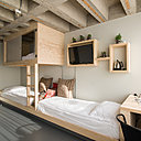 Le mobilier de rangement est intégré aux couchages. Près de la fenêtre, un coin bureau est installé à la tête du lit simple.