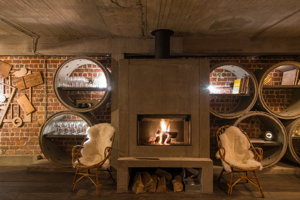 La cheminée en béton du bar est encadrée par des étagères circulaires également en béton.